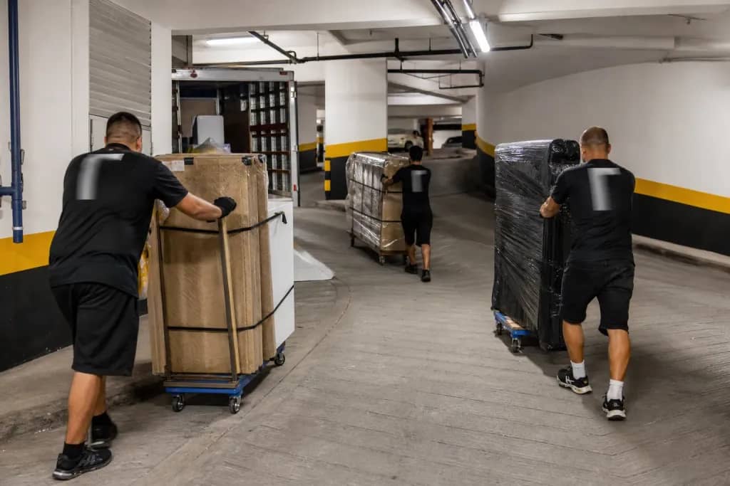 Garagem subterrânea de condomínio com equipe de mudança e móveis protegidos