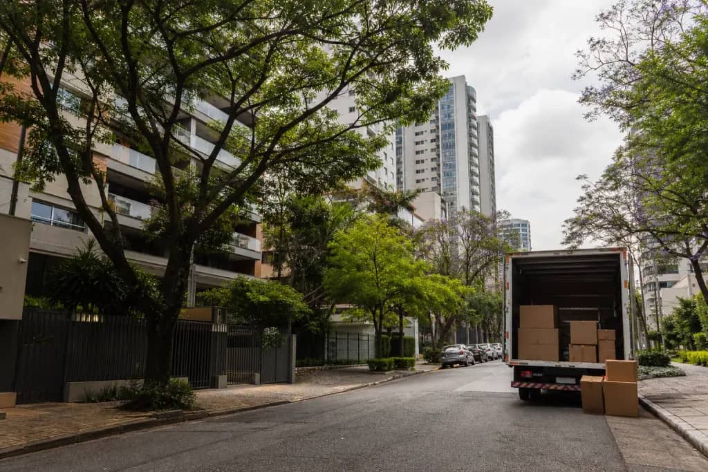 Caminhão de mudança em rua arborizada de Pinheiros com torres residenciais ao fundo
